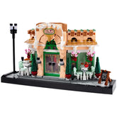 LEGO® Icons French Café set featuring a charming bistro facade with green accents, flowerpots, elegant seating, and a sidewalk.